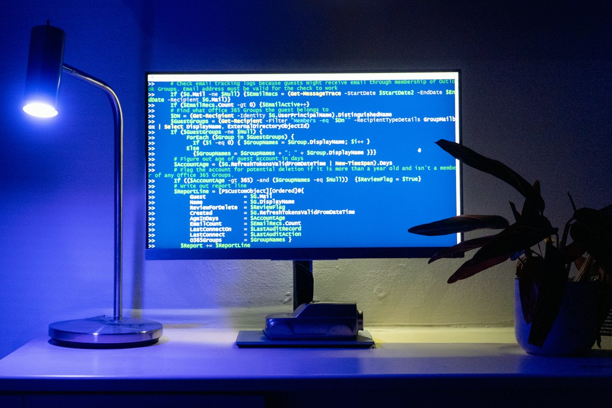 A developer's laptop with a code editor open, glasses and a notebook on the desk